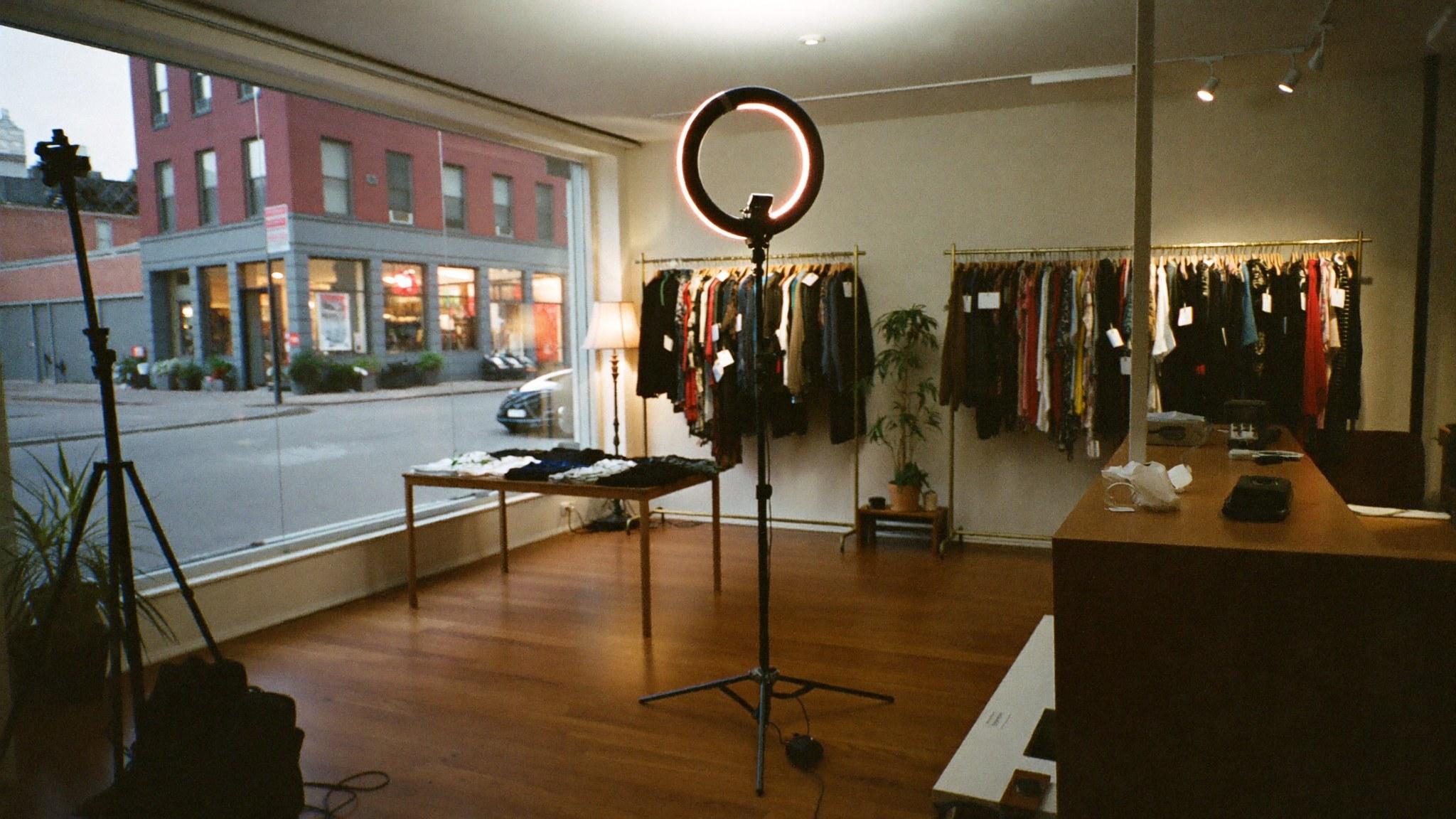 A boutique after closing with a ring light and a second tripod standing ready on the shop floor.