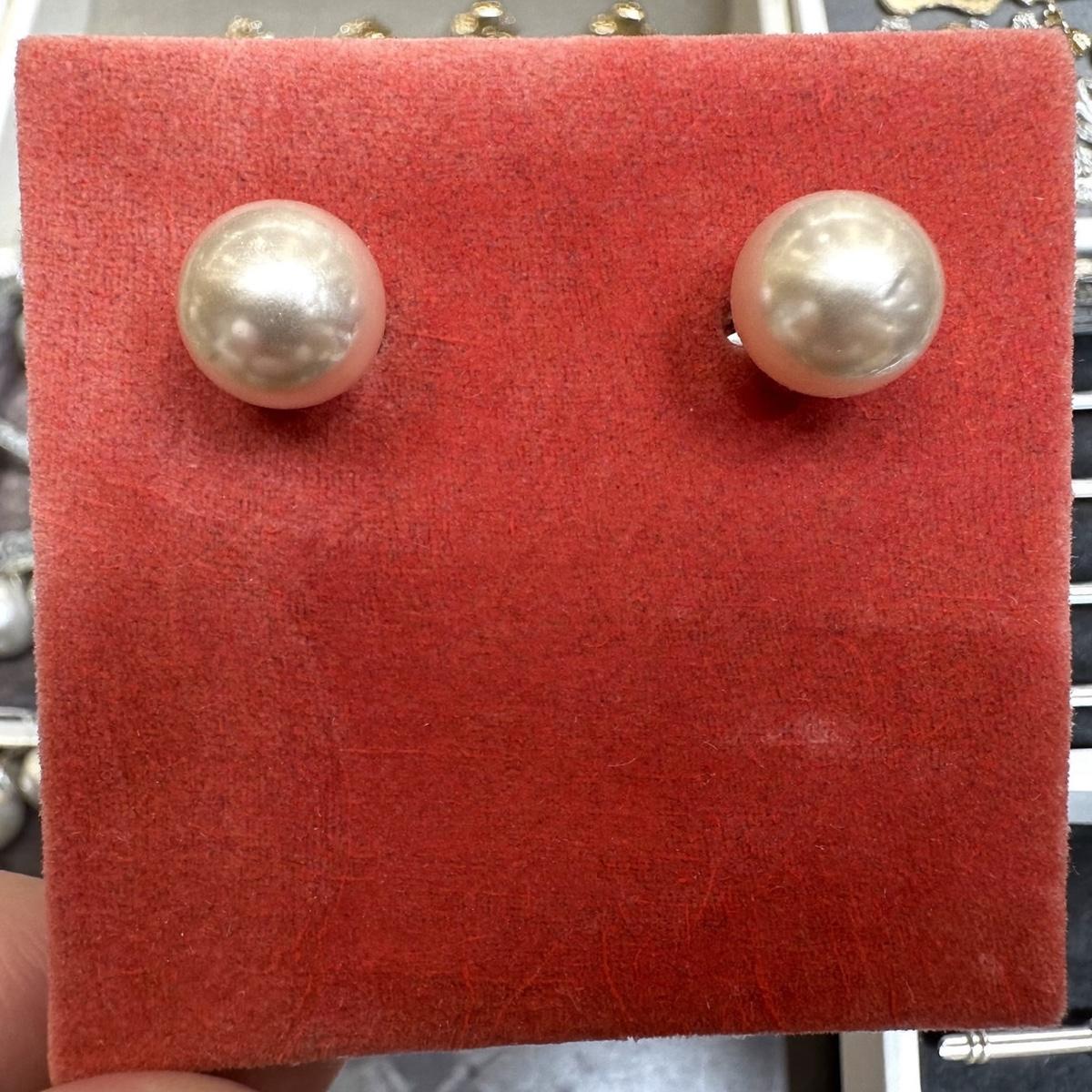 A pair of pearl stud earrings on a velvet pad.